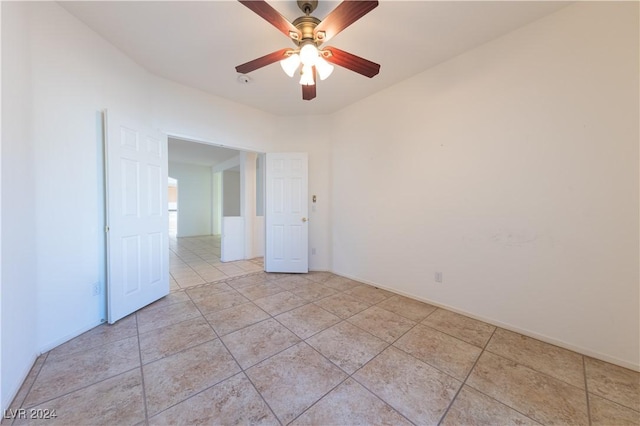 unfurnished room featuring a ceiling fan, baseboards, and light tile patterned floors