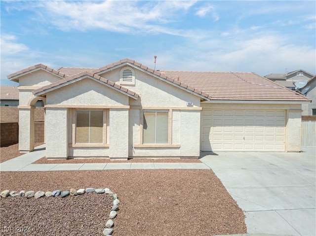 view of front of home with concrete driveway, a tile roof, an attached garage, and stucco siding