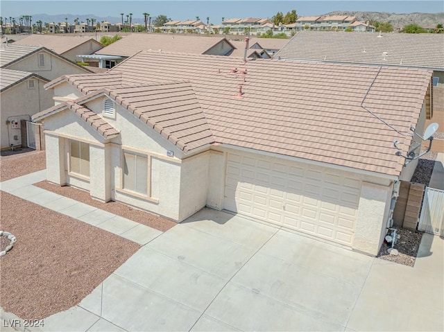 view of front facade featuring an attached garage, a tiled roof, concrete driveway, a residential view, and stucco siding