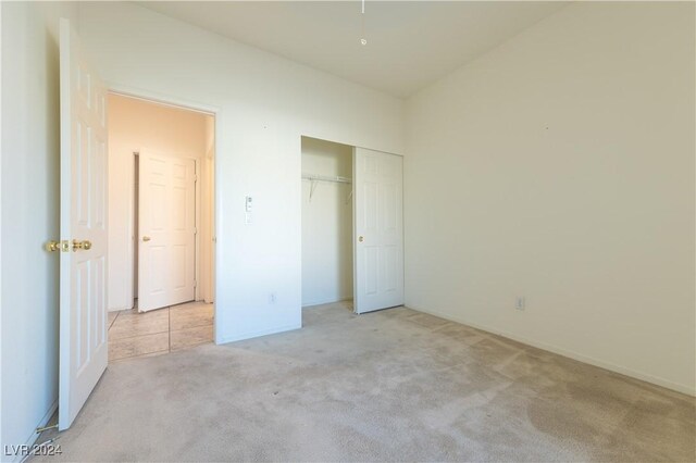 unfurnished bedroom featuring light carpet and a closet