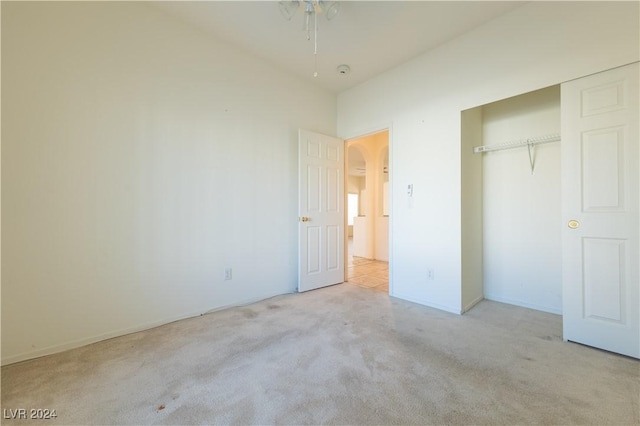 unfurnished bedroom with a closet and light colored carpet