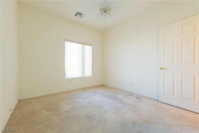 empty room featuring visible vents, ceiling fan, and light carpet