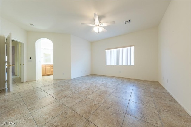 empty room featuring arched walkways, visible vents, ceiling fan, and light tile patterned floors