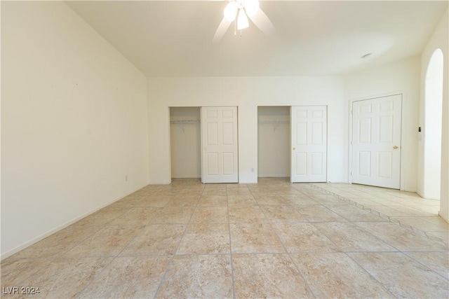 unfurnished bedroom featuring two closets and a ceiling fan