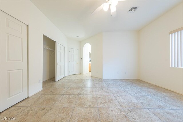 unfurnished bedroom with multiple closets, light tile patterned floors, and ceiling fan