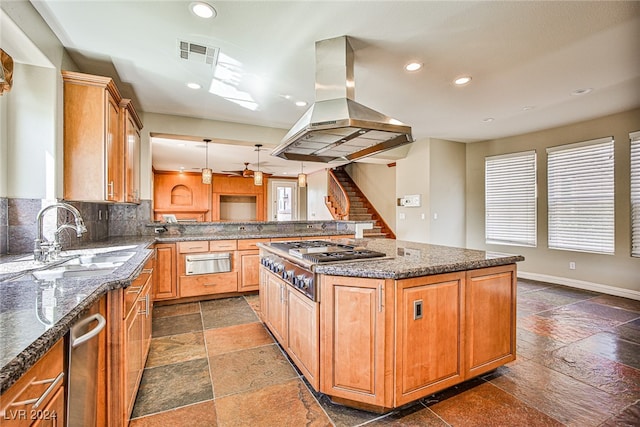 kitchen with a kitchen island, appliances with stainless steel finishes, dark tile patterned flooring, island exhaust hood, and sink