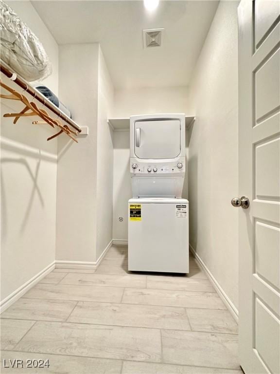 washroom featuring stacked washer / dryer and light hardwood / wood-style floors