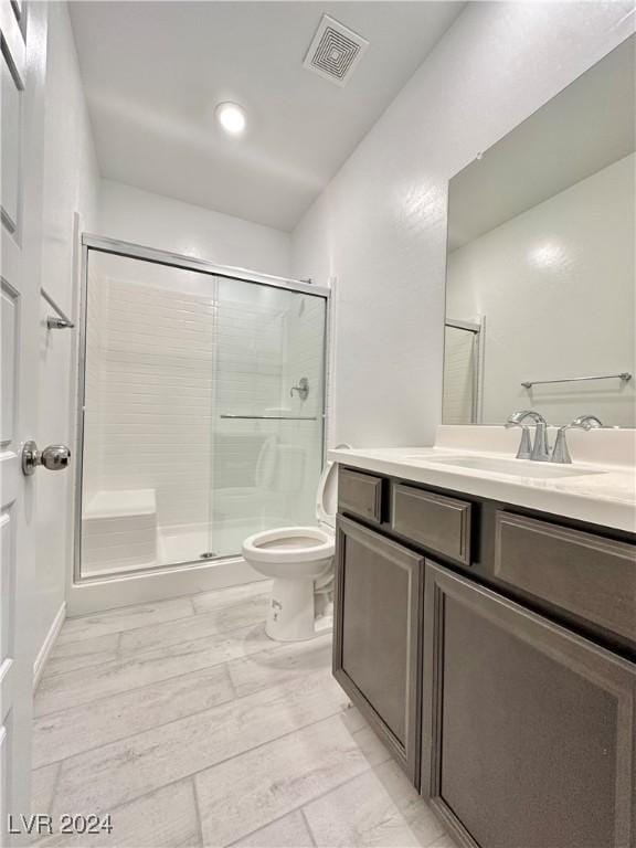 bathroom featuring vanity, toilet, and a shower with shower door