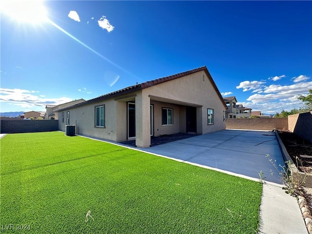 back of house with cooling unit, a yard, and a patio area