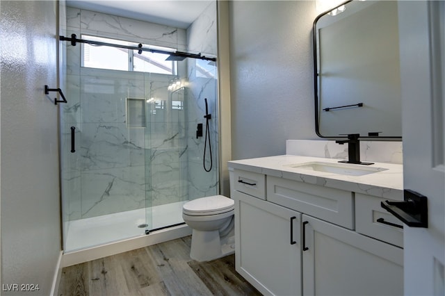 full bathroom with toilet, a marble finish shower, wood finished floors, and vanity