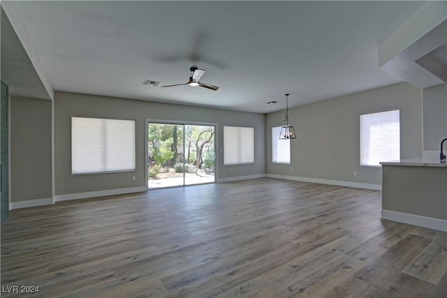 unfurnished room with a ceiling fan, visible vents, plenty of natural light, and wood finished floors