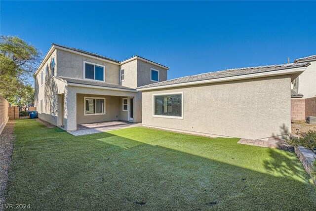 rear view of property featuring a yard and a patio area