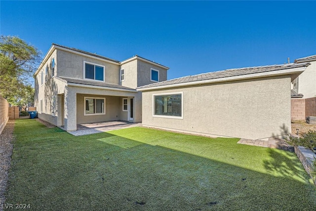 back of property with a patio area and a lawn