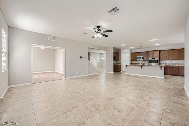 unfurnished living room featuring light tile patterned floors and ceiling fan