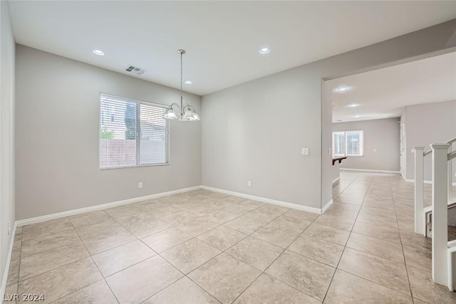 spare room with an inviting chandelier and light tile patterned flooring