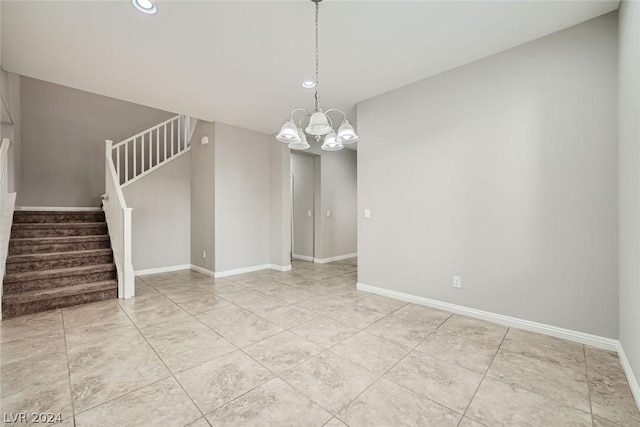 tiled spare room with a notable chandelier