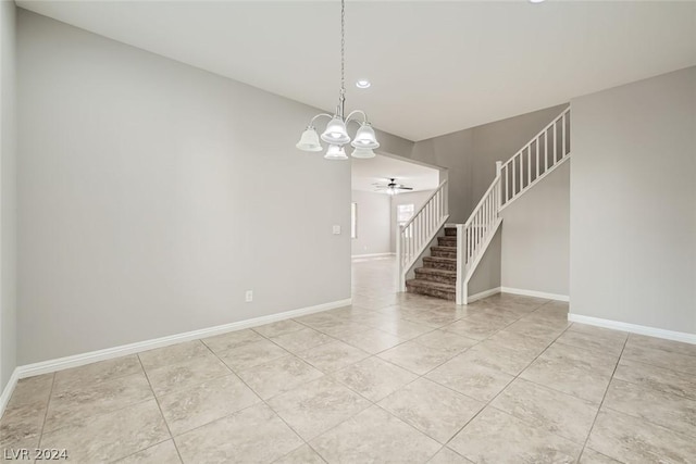 tiled spare room featuring ceiling fan with notable chandelier