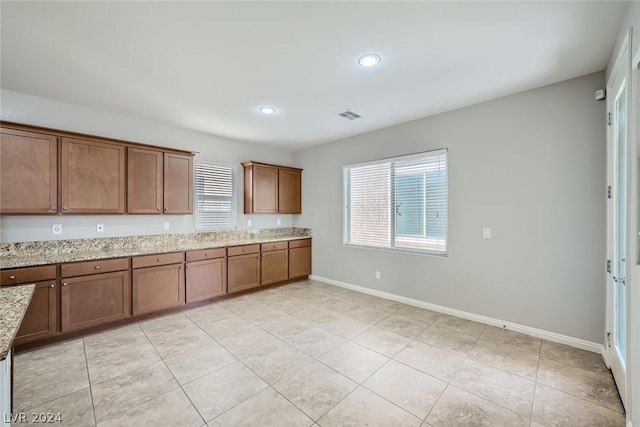 kitchen featuring light tile patterned floors, plenty of natural light, and light stone countertops