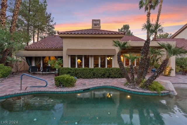 pool at dusk with a patio area