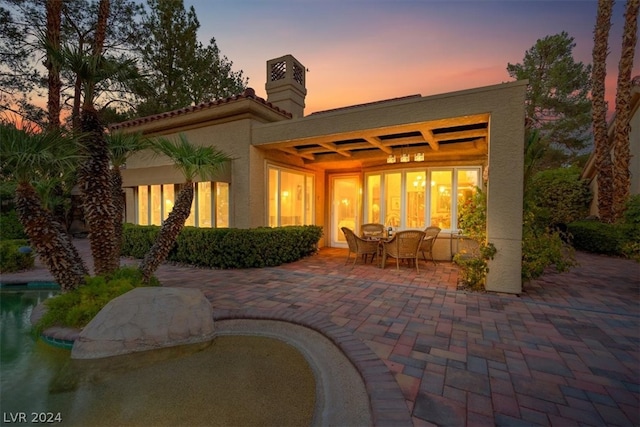 back house at dusk featuring a patio area