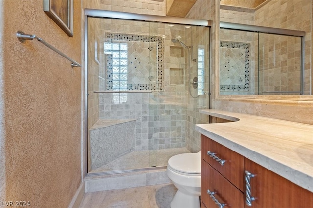 bathroom with tile patterned flooring, vanity, toilet, and a shower with shower door