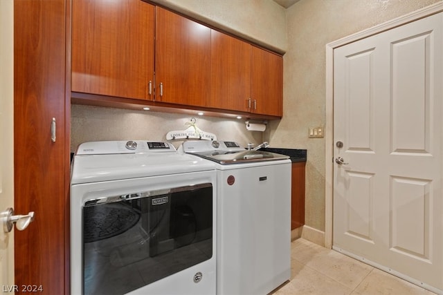 clothes washing area with cabinets, washer and dryer, and light tile patterned flooring