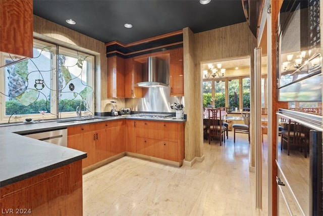 kitchen featuring wall chimney exhaust hood, stainless steel appliances, sink, a chandelier, and plenty of natural light