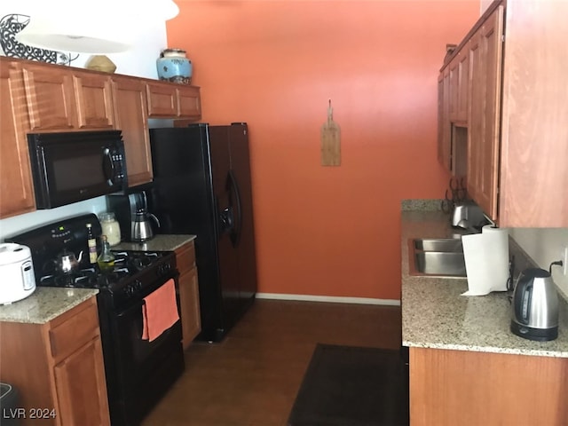 kitchen with sink, light stone countertops, black appliances, and hardwood / wood-style floors