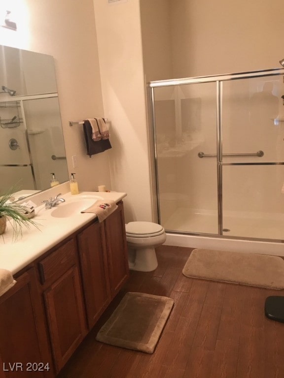 bathroom featuring walk in shower, wood-type flooring, toilet, and vanity