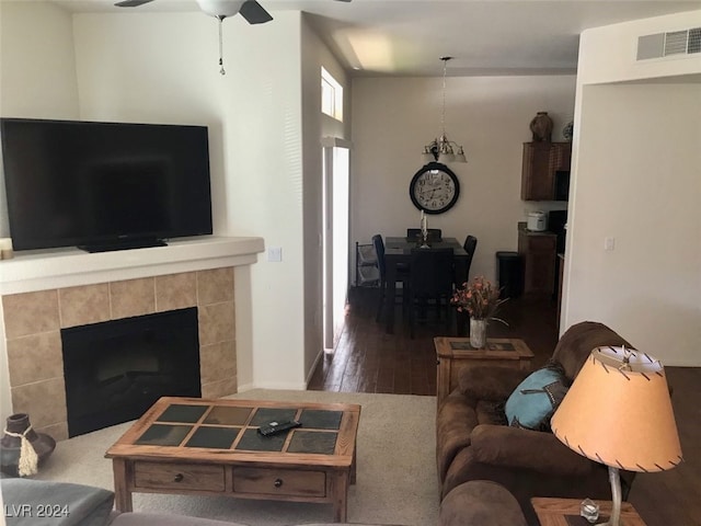 living room with a fireplace, ceiling fan, and dark wood-type flooring