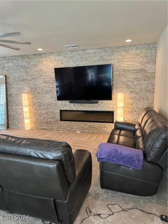 home theater with a ceiling fan, visible vents, and a stone fireplace