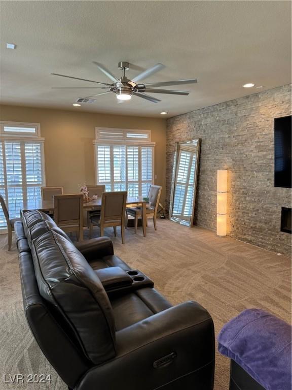 living area featuring a textured ceiling, carpet flooring, a wealth of natural light, and a ceiling fan