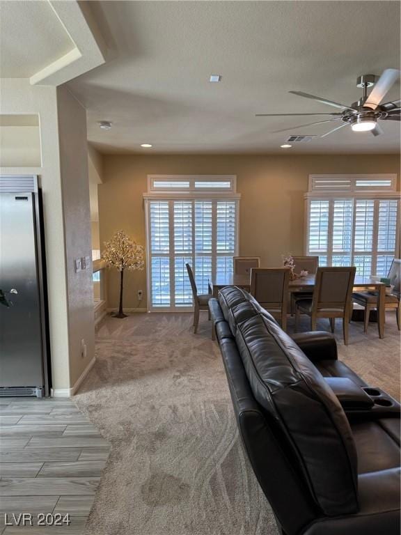 living area featuring light carpet, plenty of natural light, visible vents, and baseboards