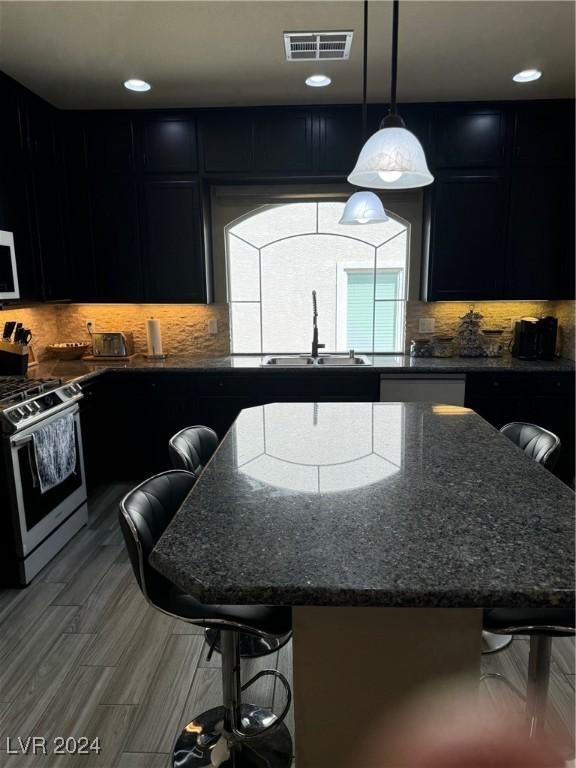 kitchen featuring a sink, gas range, a breakfast bar, and dark cabinets