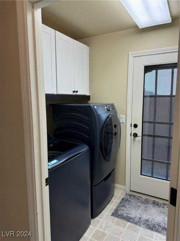 clothes washing area featuring baseboards, light tile patterned flooring, cabinet space, and washer and dryer