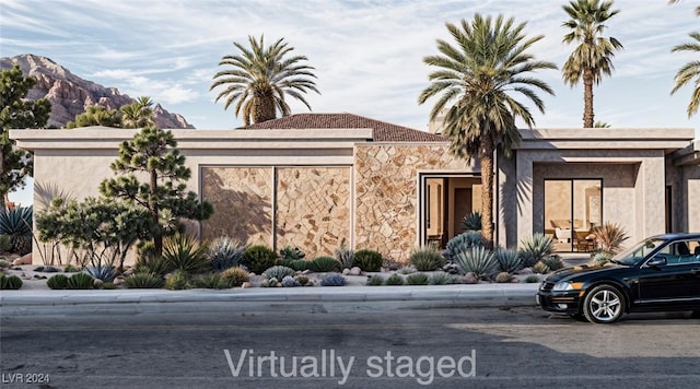 view of front of house featuring stone siding, a mountain view, and stucco siding