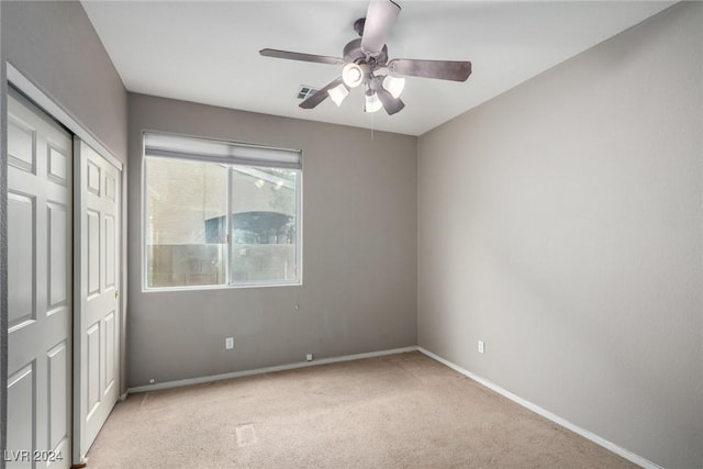 unfurnished bedroom featuring ceiling fan, a closet, and light carpet