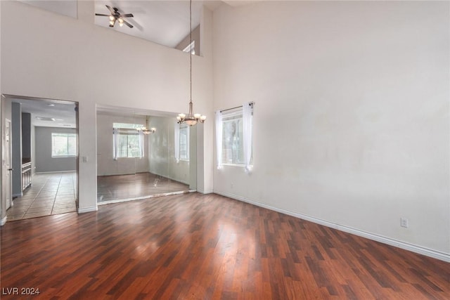 interior space featuring a high ceiling, ceiling fan with notable chandelier, and dark hardwood / wood-style flooring