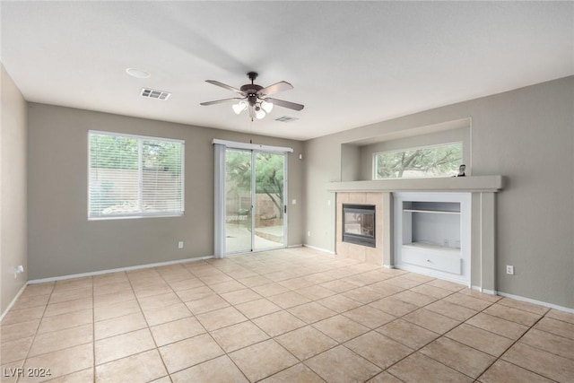 unfurnished living room featuring a tile fireplace, light tile patterned floors, and ceiling fan