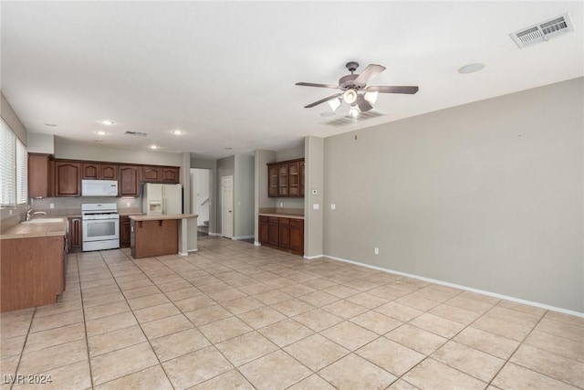 kitchen featuring light tile patterned floors, sink, white appliances, ceiling fan, and a center island