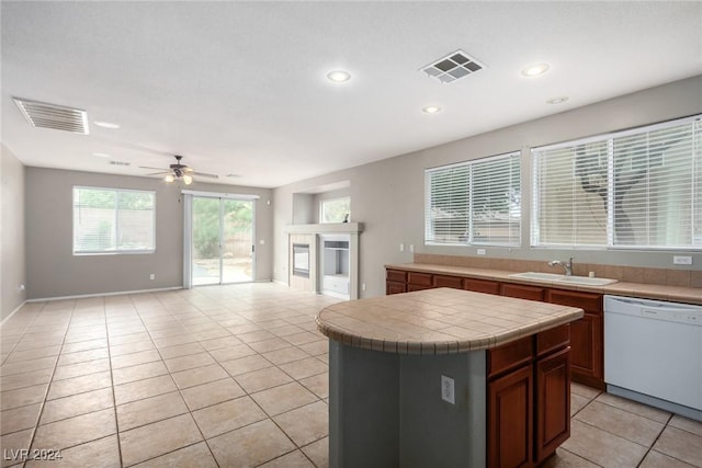 kitchen featuring light tile patterned flooring, sink, tile countertops, a center island, and dishwasher