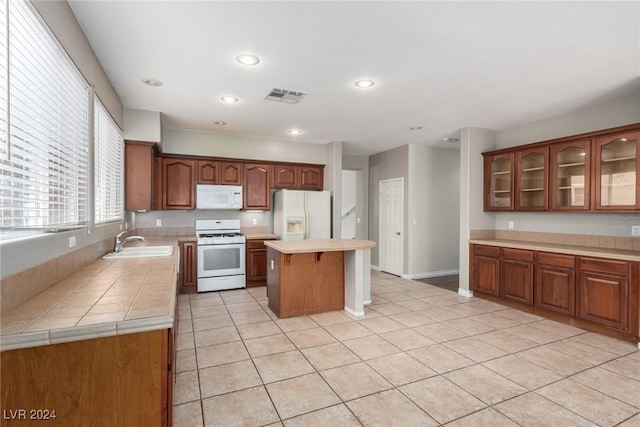 kitchen with sink, white appliances, light tile patterned flooring, and a kitchen island