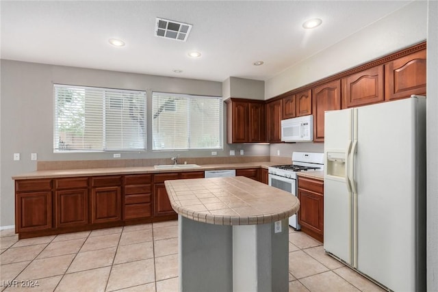 kitchen featuring light tile patterned flooring, a kitchen island, tile countertops, sink, and white appliances