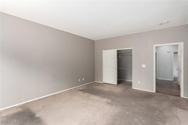 unfurnished bedroom with a closet and dark colored carpet