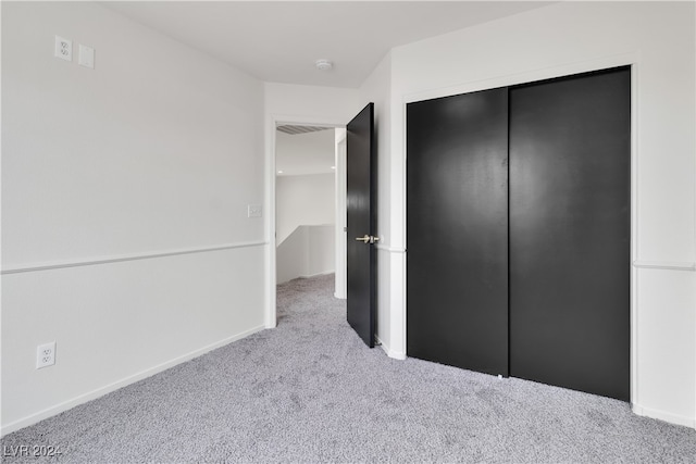 unfurnished bedroom featuring light colored carpet and a closet