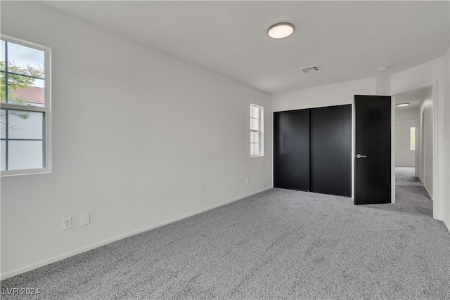 unfurnished bedroom with light colored carpet and a closet