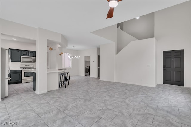 unfurnished living room featuring washer / dryer and ceiling fan with notable chandelier