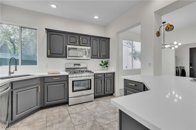 kitchen featuring sink, gray cabinetry, plenty of natural light, appliances with stainless steel finishes, and washer and clothes dryer