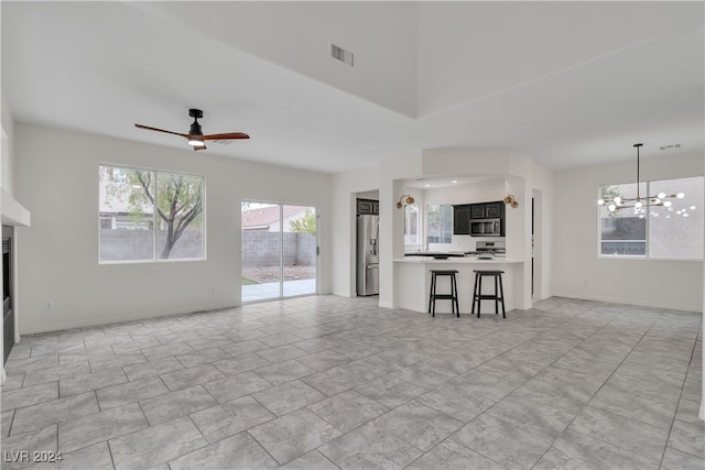 unfurnished living room with ceiling fan with notable chandelier