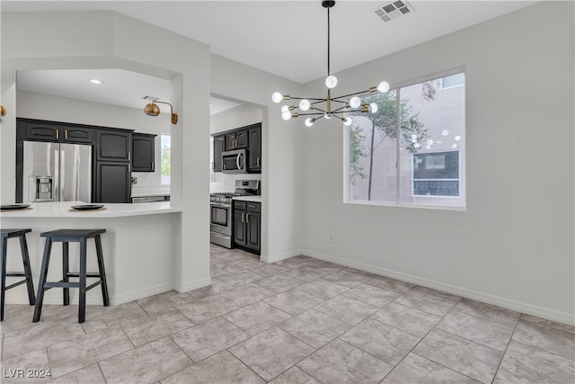 kitchen with a notable chandelier, a kitchen bar, hanging light fixtures, and appliances with stainless steel finishes